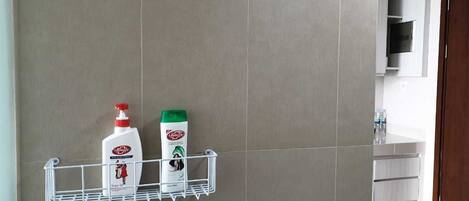 A bathroom with a wall-mounted shelf holding two bottles of lotion and a bottle of shampoo.