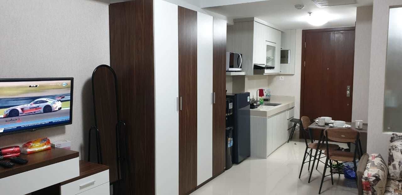 A compact kitchen with a microwave, refrigerator, and dining area with chairs and a table.