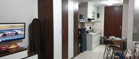 A compact kitchen with a microwave, refrigerator, and dining area with chairs and a table.