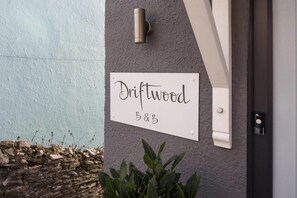 A sign reading "Driftwood B&B" mounted on a textured wall.