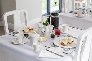 A breakfast setting with a coffee pot, eggs, and various beverages on a table.