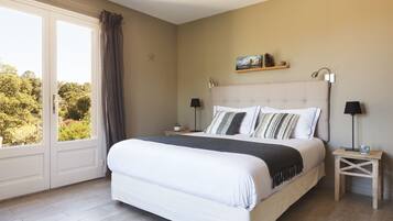 A bedroom with a large bed, two bedside tables, a nightstand, a window with curtains, and a starfish decoration on the wall.