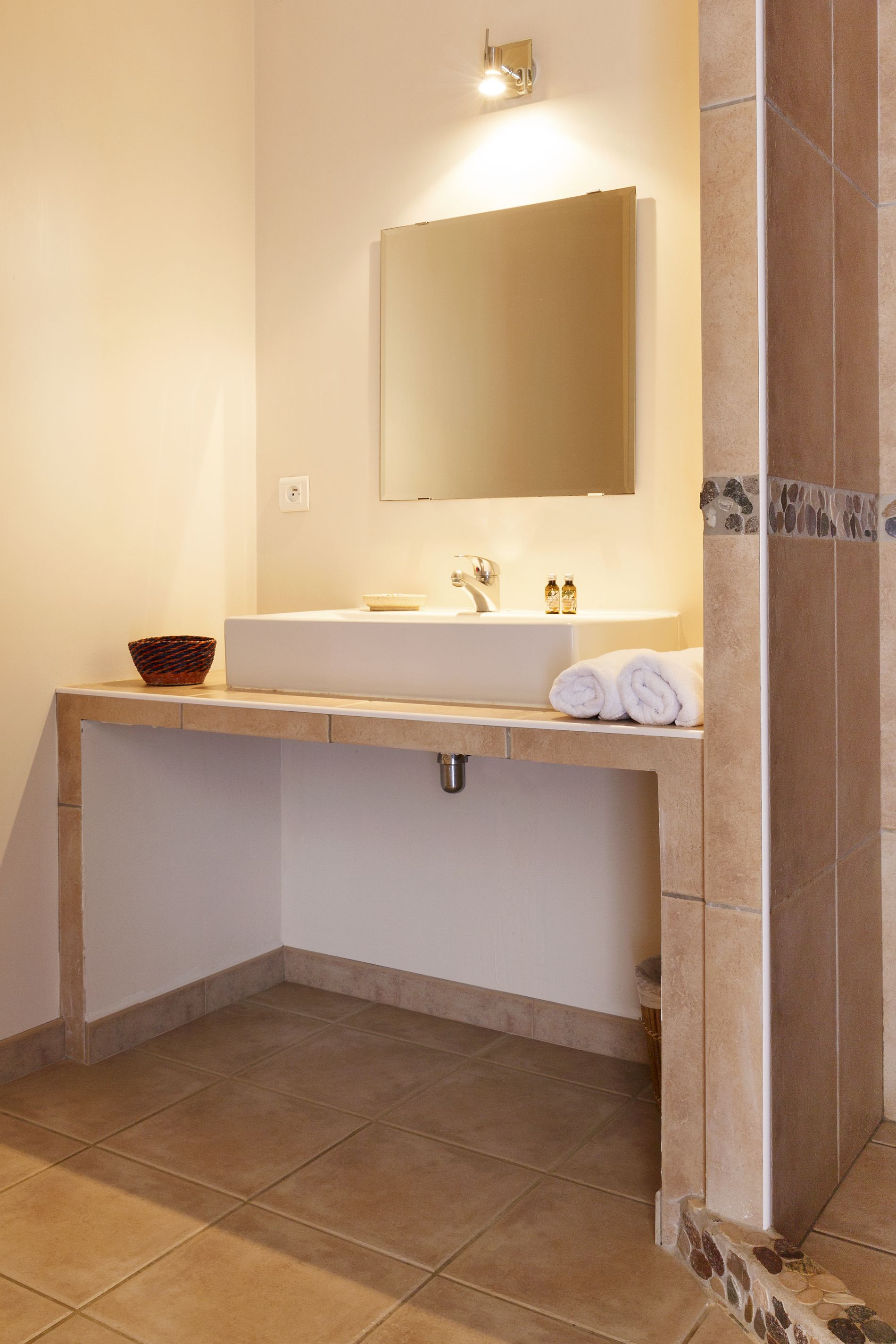 Un baño con un lavabo blanco, un espejo y suelo de baldosas.