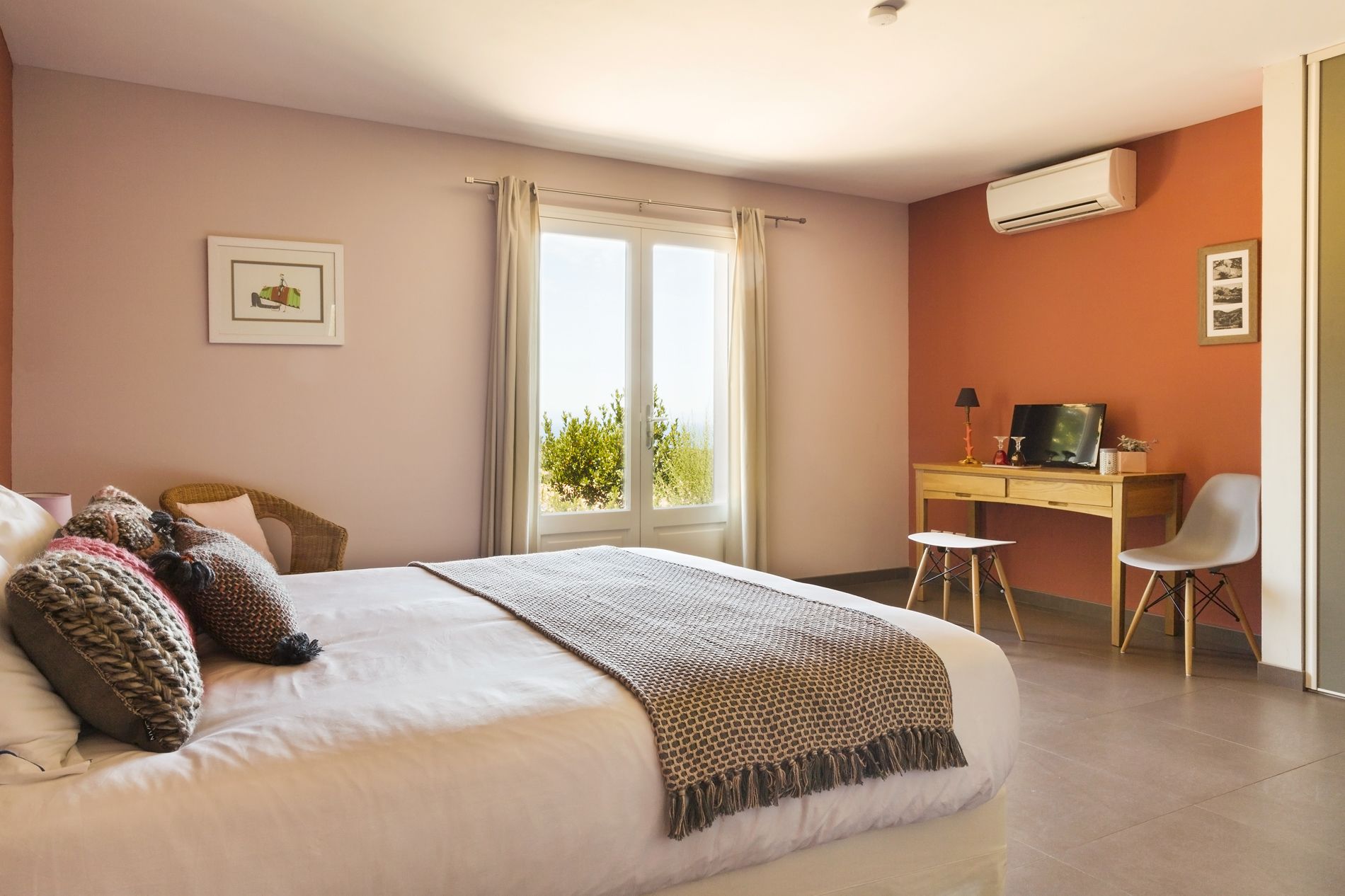 A bedroom with a bed, a desk, a chair, and a window with curtains.