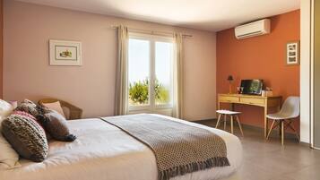 A bedroom with a bed, a desk, a chair, and a window with curtains.