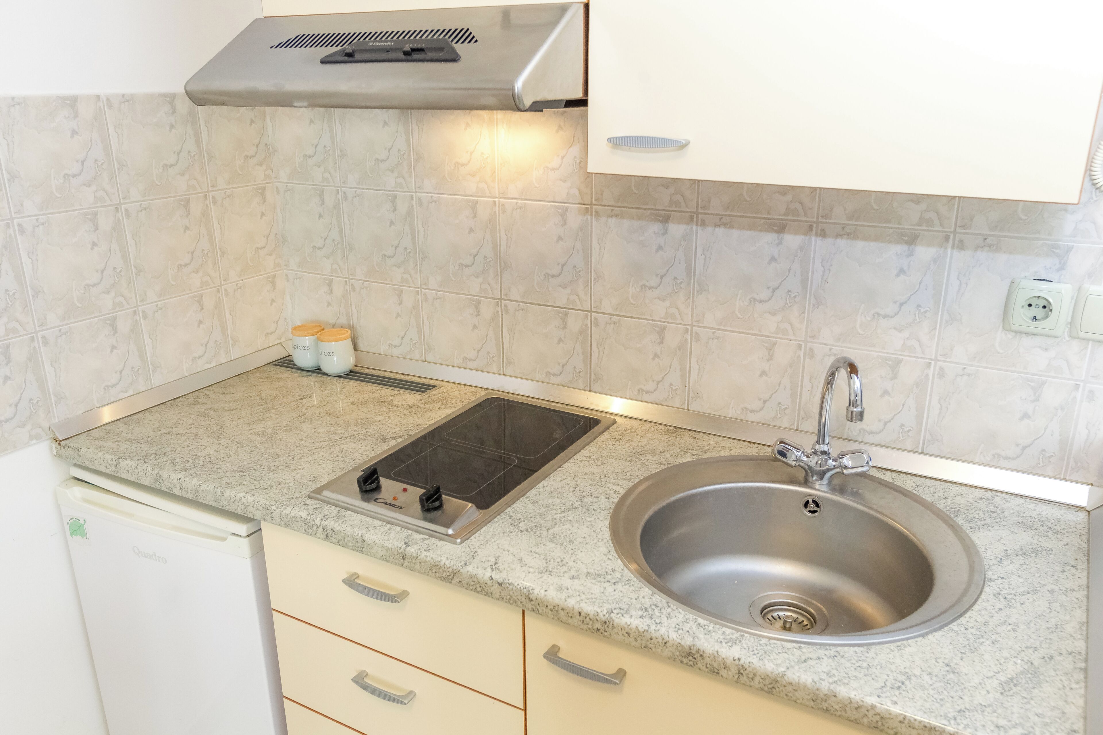 A kitchen with a stainless steel sink, a built-in stovetop, and a microwave.