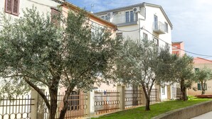 A residential building with a beige facade, a balcony, and a metal fence. - Apartments in City Center Ventus (Novalja)