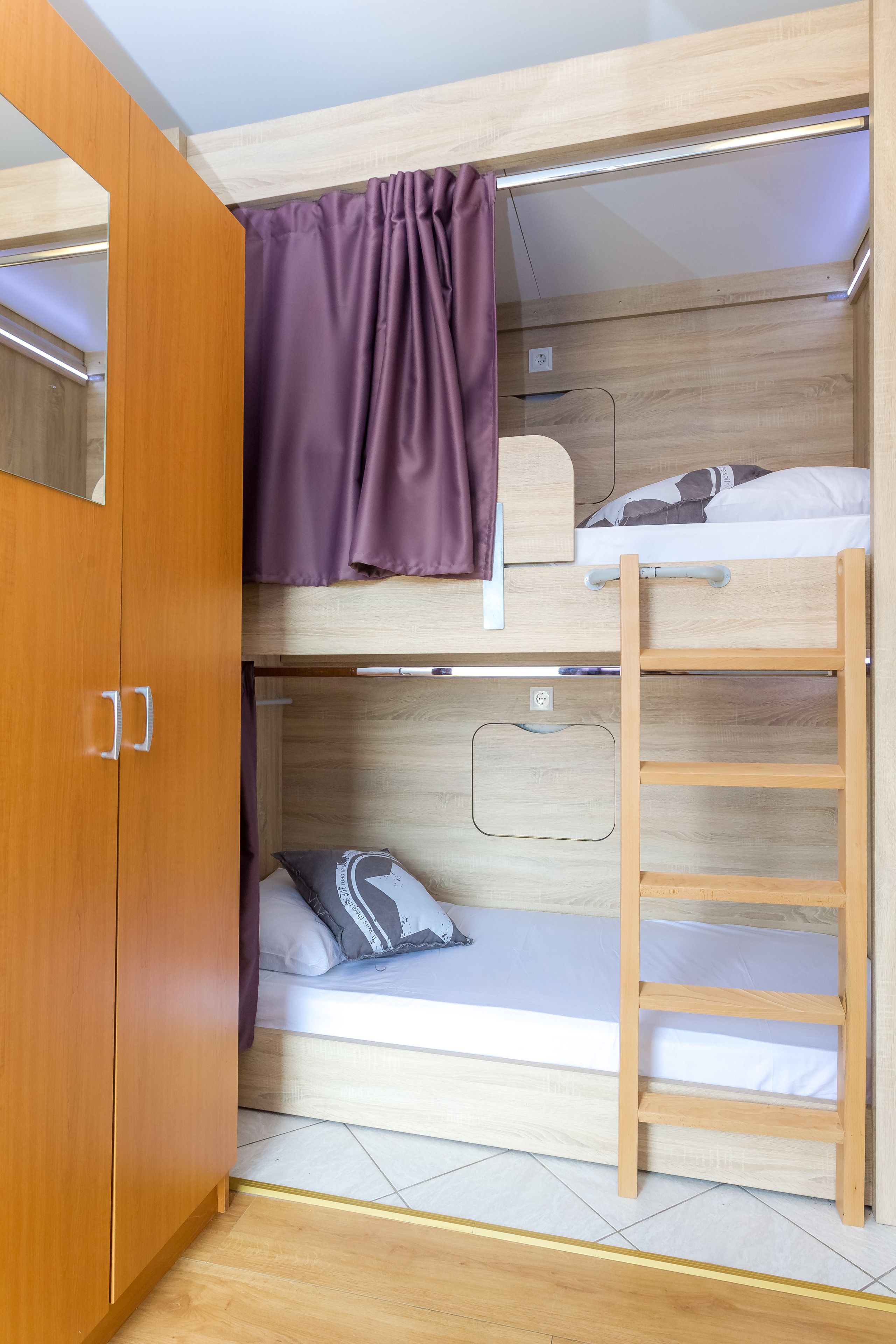 A bunk bed room with a wooden wardrobe and a ladder.