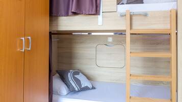 A bunk bed room with a wooden wardrobe and a ladder.