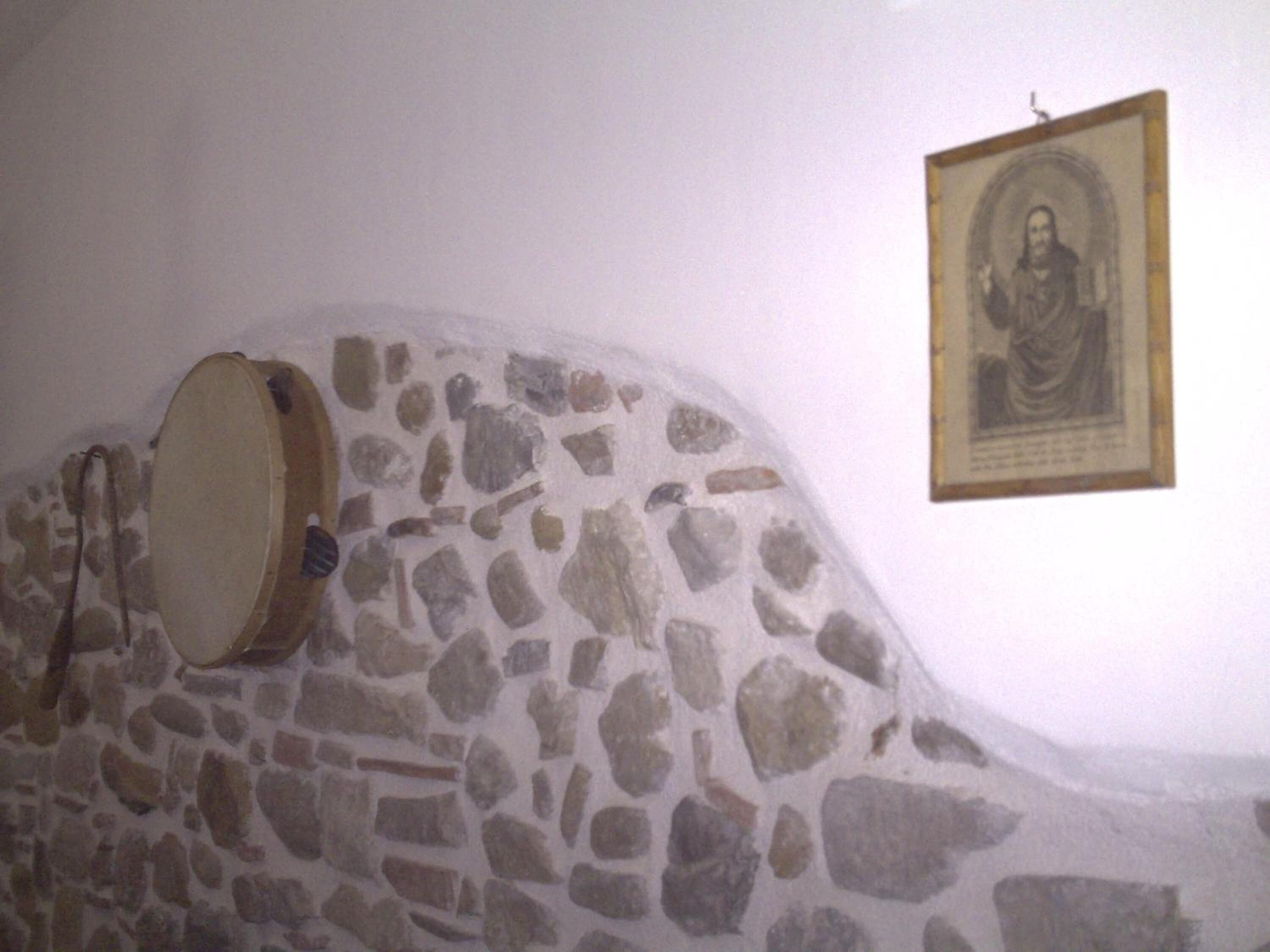 A stone wall with a drum and a framed picture.
