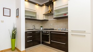 A modern kitchen with dark cabinetry, a stainless steel range hood, and a built-in oven. - Maru Apartments (Novalja)