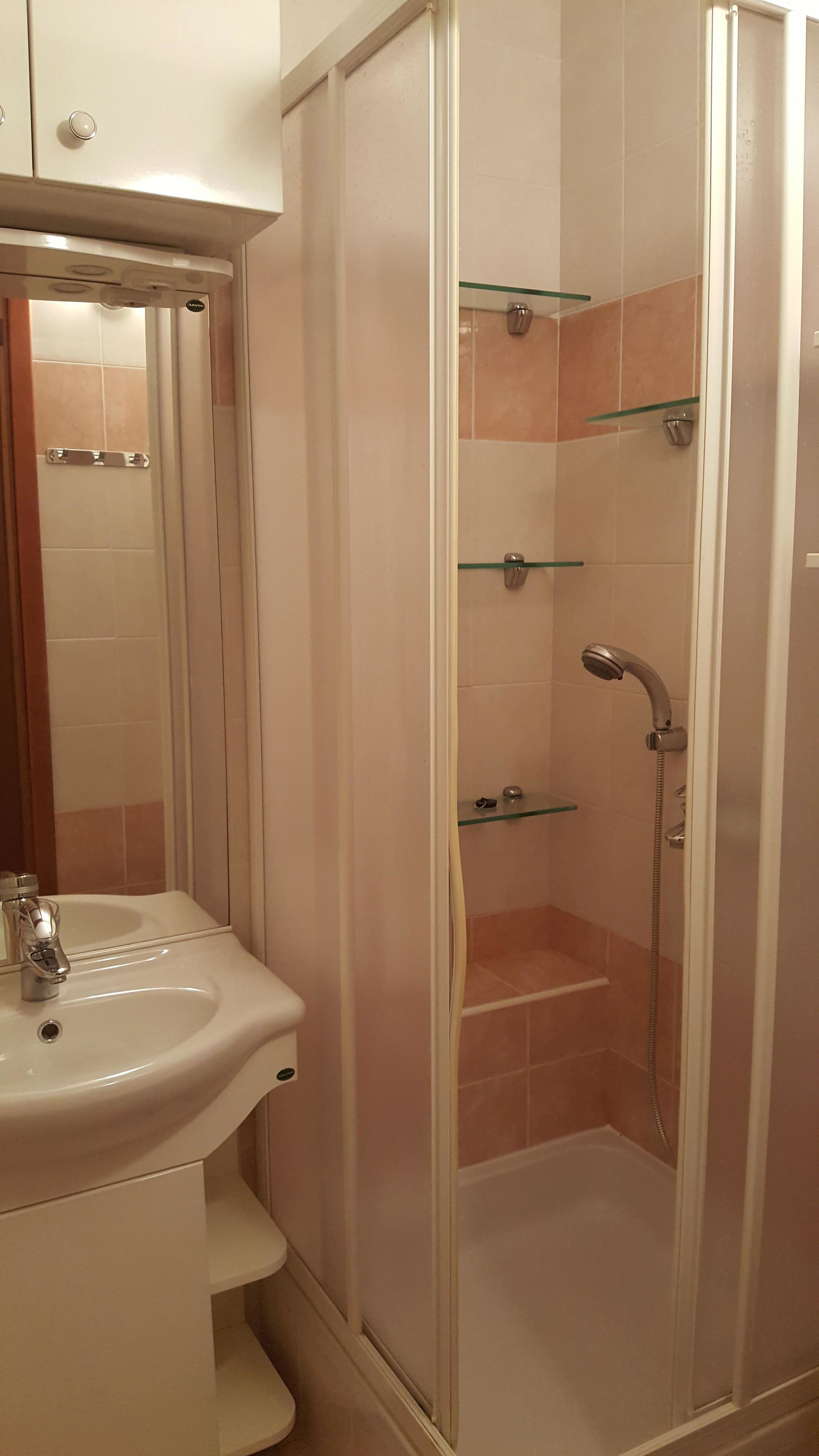 A bathroom with a white sink, a glass shower enclosure, and a mirror above the sink.