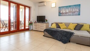 A living room with a sofa, a TV, and a painting on the wall. - Maru Apartments (Novalja)