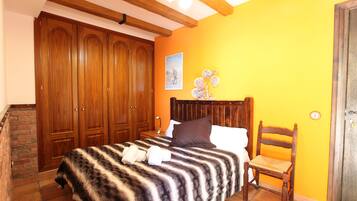 Un dormitorio con una cama, un armario de madera, una pared de ladrillo y una pared amarilla.