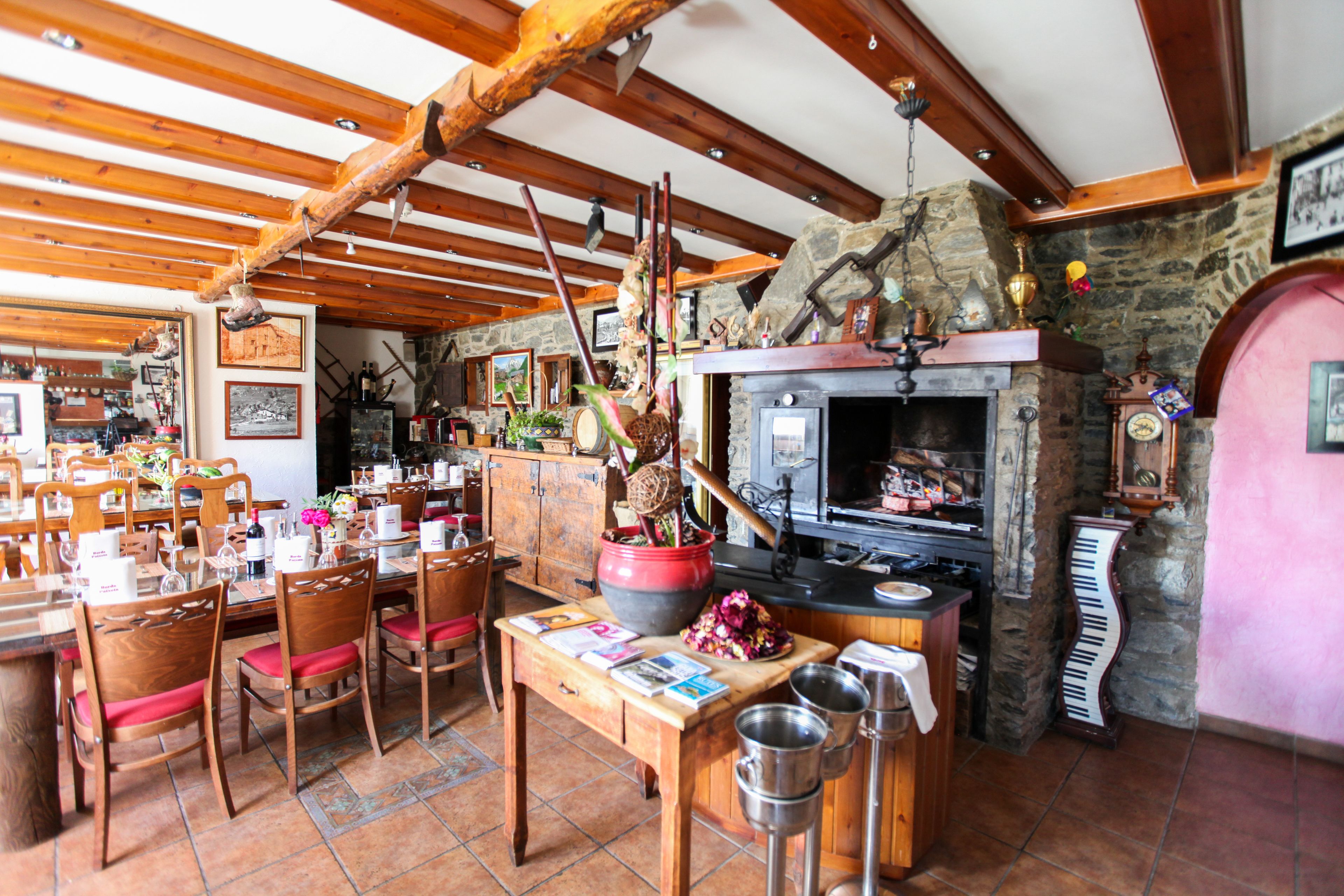 A rustic dining area with wooden furniture, a stone fireplace, and a variety of decorative items.