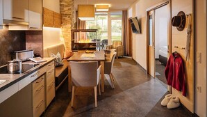A modern kitchen with a dining area, a fireplace, and a view of the outdoors. - Guthof Lutz Appartement mit kostenlosen Sommerbergbahnticket Mai bis Oktober (Schattwald)