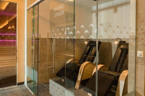 Zona de spa con sillones de masaje y un muro de cristal con diseño de montaña.