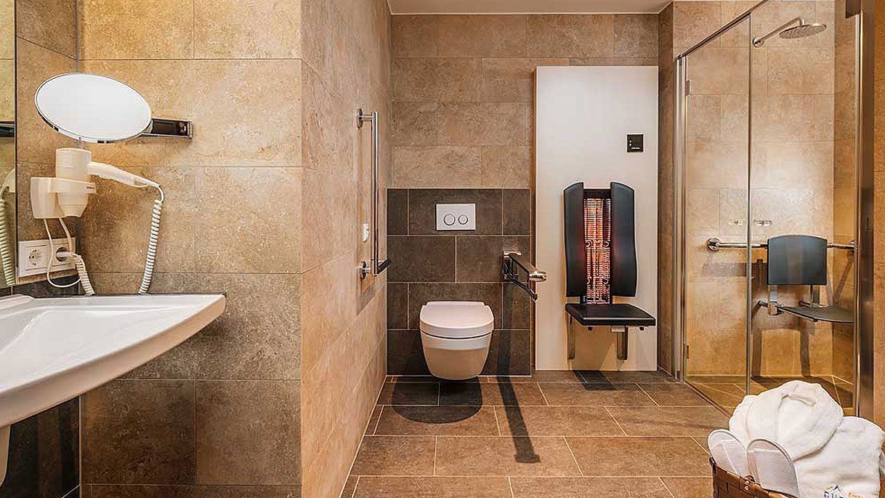 Un baño moderno con lavamanos, espejo, secador de pelo, inodoro, ducha y toallero.