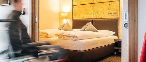 A hotel room with a wooden headboard, two beds, and a nightstand with a lamp.