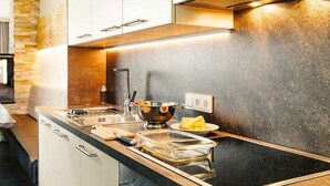A modern kitchen with a black stovetop, white cabinets, and a granite countertop. - Guthof Lutz Appartement mit kostenlosen Sommerbergbahnticket Mai bis Oktober (Schattwald)