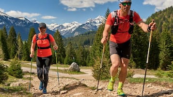 Deux personnes font de la randonnée sur un sentier rocailleux, avec une chaîne de montagnes en arrière-plan.