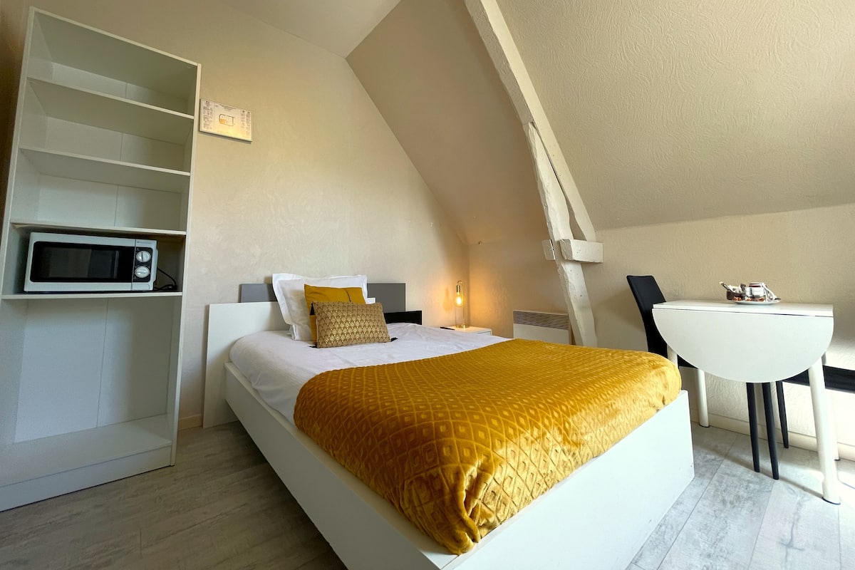 Une chambre avec un lit, un four à micro-ondes, une petite table et une chaise.