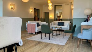 Un salon moderne avec un canapé, des fauteuils, une table basse et des plantes décoratives.