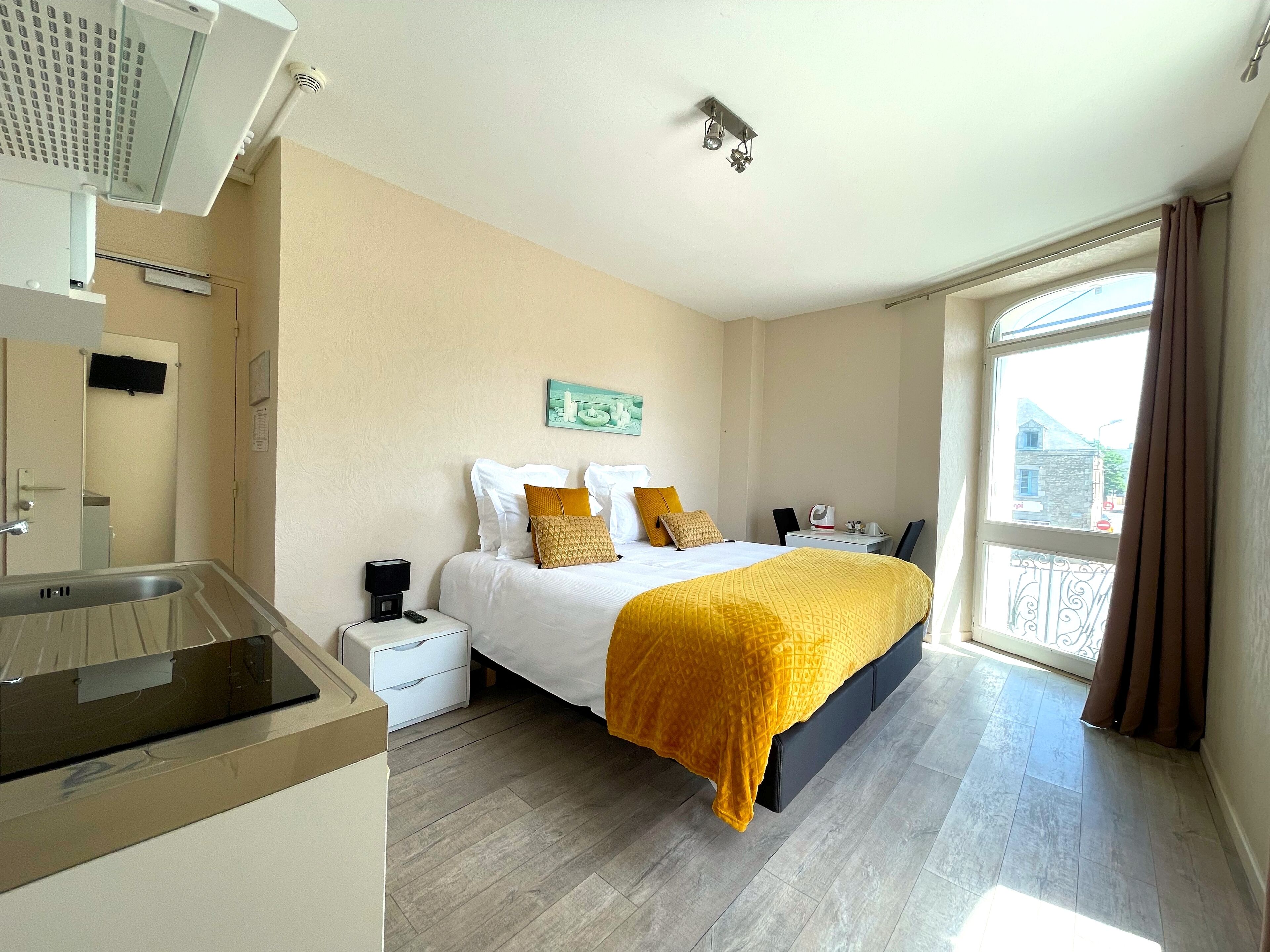 Een hotelkamer met een bed, nachtkastje en een raam met gordijnen.