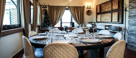A dining room with a round table set for six, surrounded by six quilted chairs.