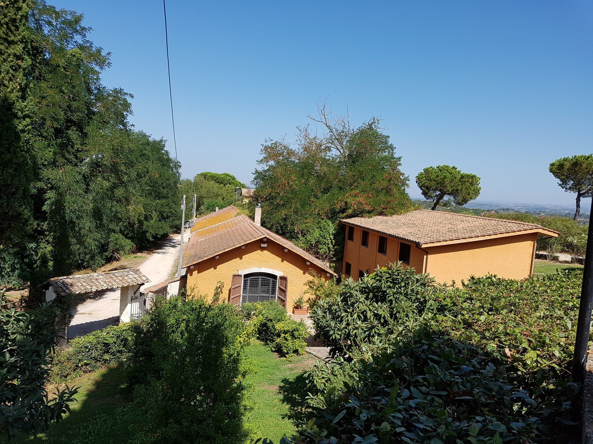 Ein ländliches Haus mit Ziegeldach, umgeben von üppigem Grün und Bäumen.
