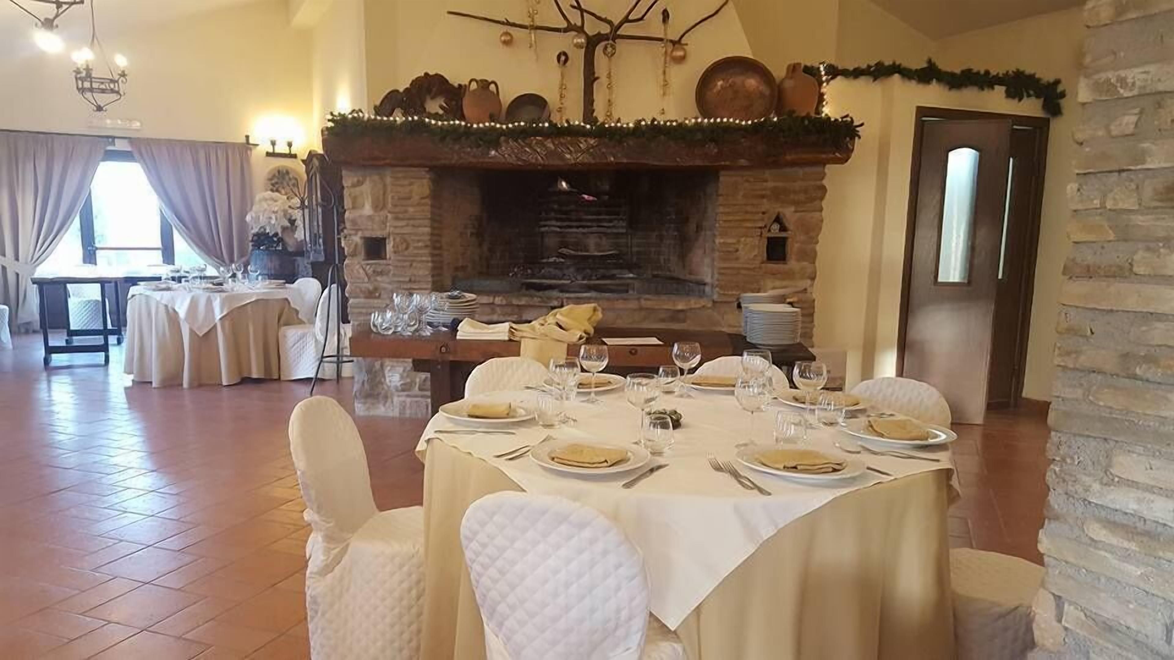 A dining area with a stone fireplace, white tablecloths, and chairs.