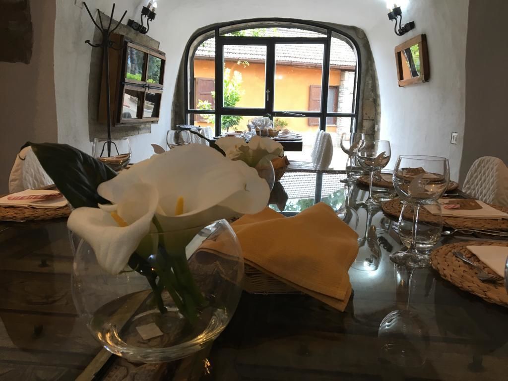 Una mesa de comedor dispuesta con flores blancas, copas de vino y un jarrón.