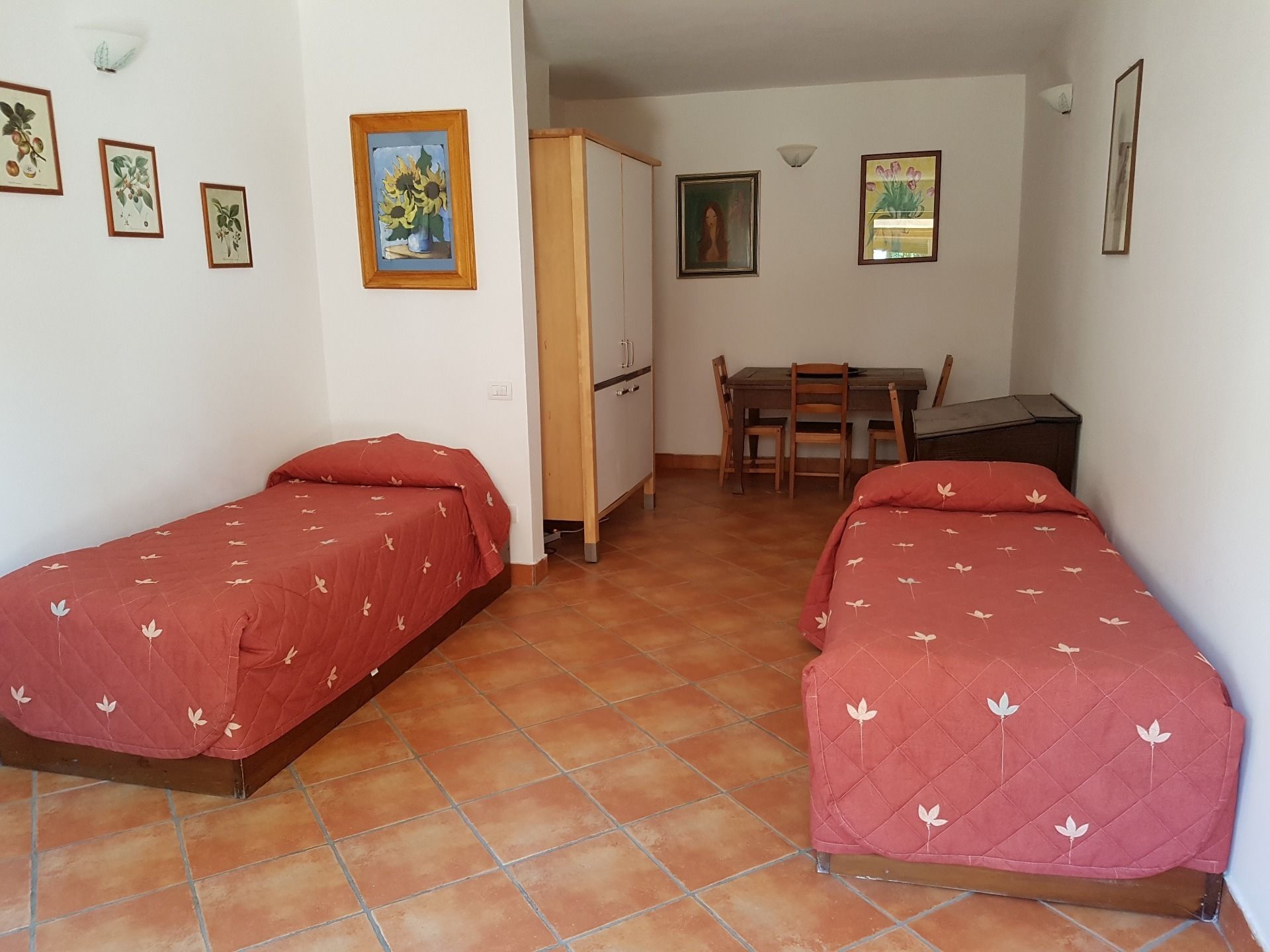 Una habitación con dos camas individuales, un escritorio de madera, una silla y un armario.