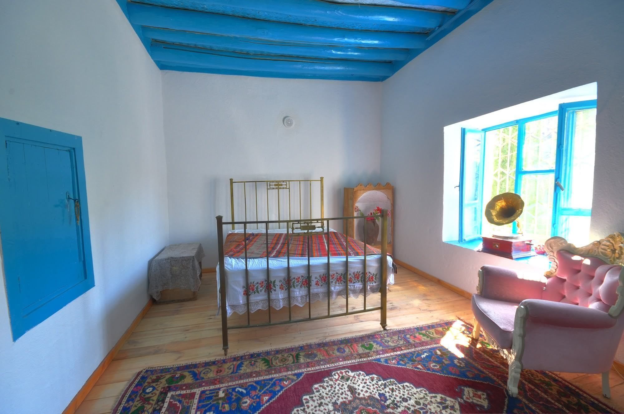 A room with a bed, a chair, a window with curtains, and a rug.