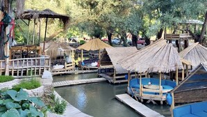 Een resort aan de rivier met houten terrassen en hutten met rieten daken.