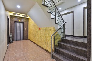 Un interior moderno con una escalera, un ascensor y suelo de baldosas.