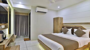 A modern hotel room with a bed, a wooden wardrobe, a flat-screen TV, and a ceiling fan.