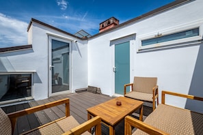 A rooftop patio with wooden furniture, a sliding glass door, and a blue door. - Flospirit - Magnifico (Florence)