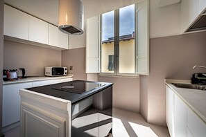Une cuisine moderne équipée d’une cuisinière intégrée, d’un four à micro-ondes et d’une fenêtre avec volets.