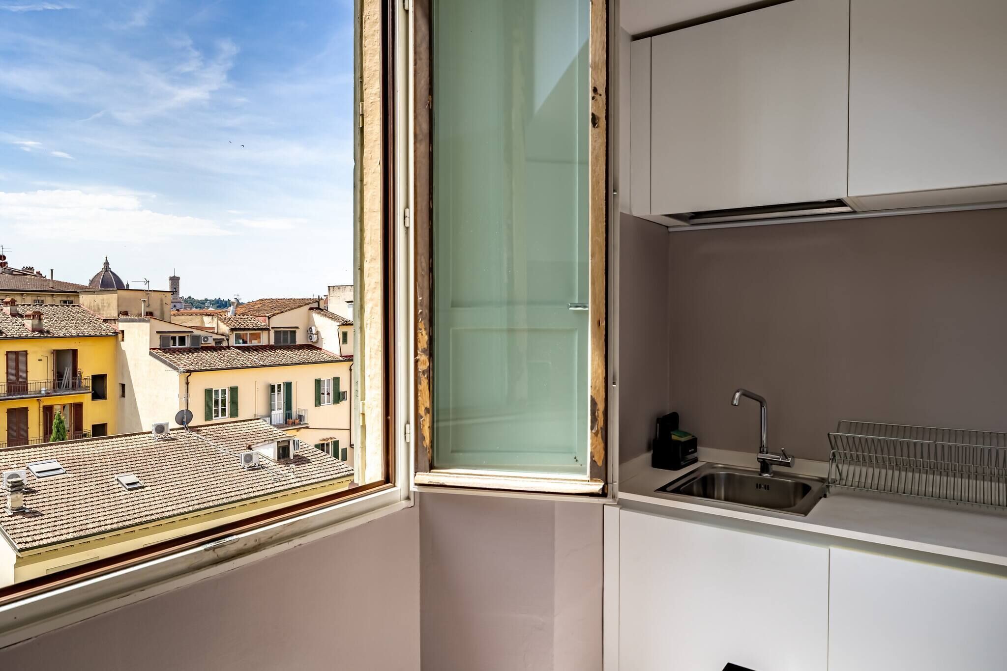 A kitchen with a window, a sink, and a view of buildings.