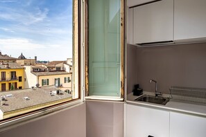 Une cuisine avec une fenêtre, un évier et une vue sur les immeubles.