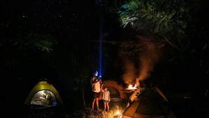 Um camping com tendas e uma fogueira.