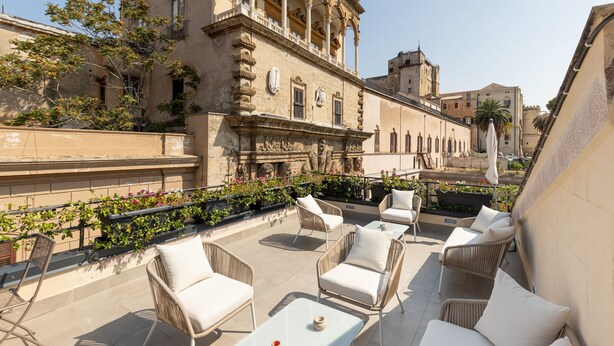 Une terrasse sur le toit, dotée de mobilier en osier et offrant une vue sur des bâtiments historiques.
