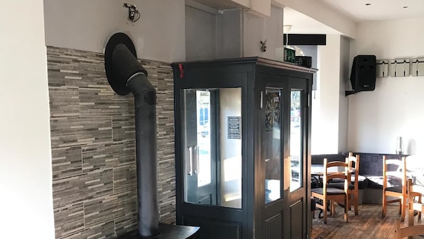 A modern living room with a wood-burning stove, a glass-fronted cabinet, and a dining area with wooden chairs. - Marlborough Hotel (Hull)