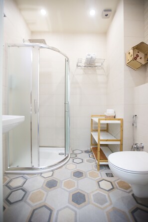 A modern bathroom with a glass-enclosed shower, a toilet, and a sink.