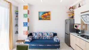 Een moderne keuken met een inbouwkoelkast, een zithoek met een bank, en een muur met kleurrijke kunstwerken.
