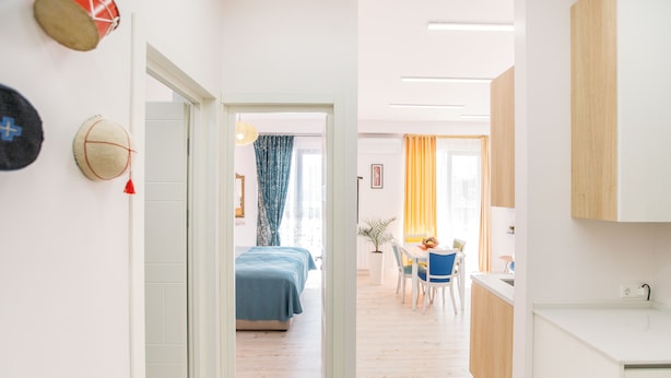 Een modern appartement met een gang die leidt naar een slaapkamer, een eethoek en een keuken.