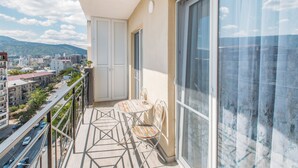Een balkon met een tafel en stoelen, en een stadszicht met een deur.