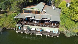 A large wooden houseboat with multiple decks, outdoor seating, and a dock extending into a body of water. - Sweet Home River Hotel (Sile)