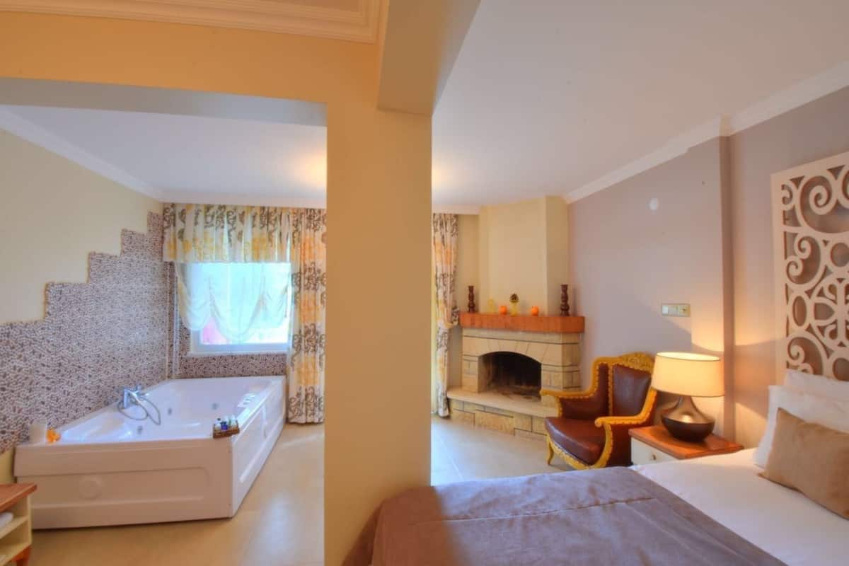 Habitació d'hotel amb una banyera gran, una llar de foc, un llit i una cadira.